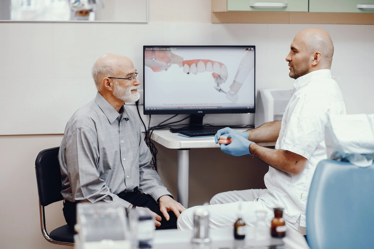 Senior man learning about All on 4 implants from dentist during consultation