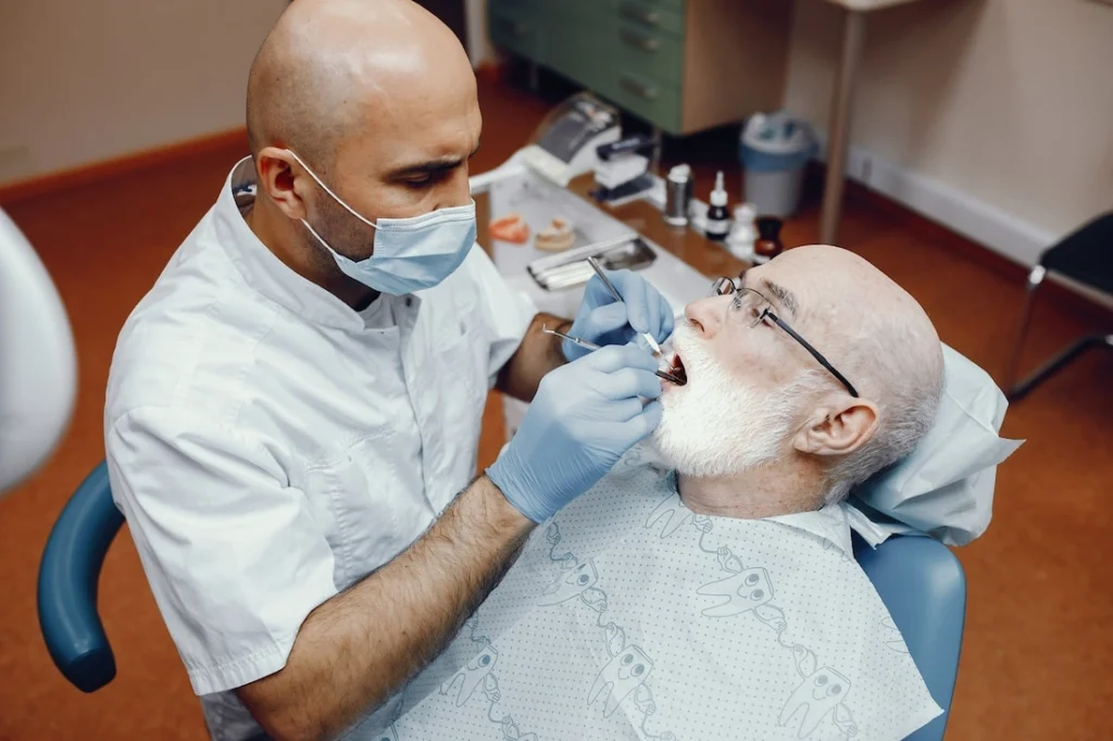 Male dentist performing a dental implant examination on a senior man in a dental chair.